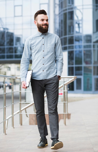 Confident young businessman walking in front of corporate building