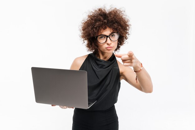 Confident young businesswoman in eyeglasses holding laptop