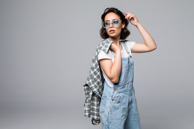 Confident young casual woman looking through sunglasses isolated