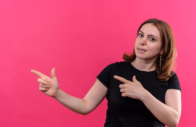 Confident young casual woman pointing at left side on isolated pink space