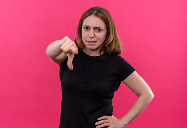 Confident young casual woman pointing  with hand on waist on isolated pink space with copy space