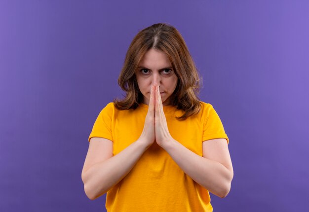 Уверенная молодая случайная женщина, сложив руки в жесте молитвы на изолированном фиолетовом пространстве с копией пространства