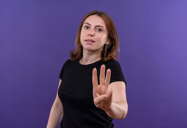 Уверенная молодая случайная женщина, показывающая троих на изолированном фиолетовом пространстве с копией пространства