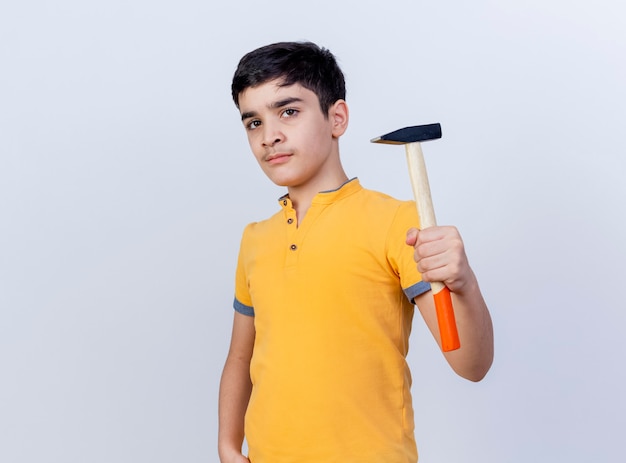 Confident young caucasian boy holding hammer looking at camera isolated on white background with copy space