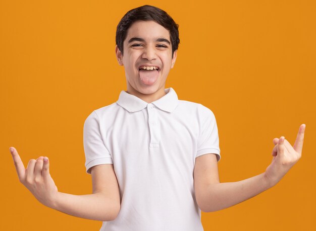 Уверенный молодой кавказский мальчик показывает язык, делая знак рок