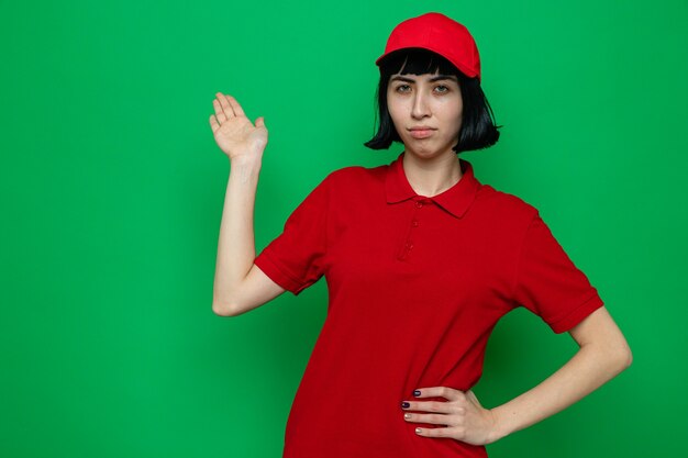 Confident young caucasian delivery girl pointing back with hand 