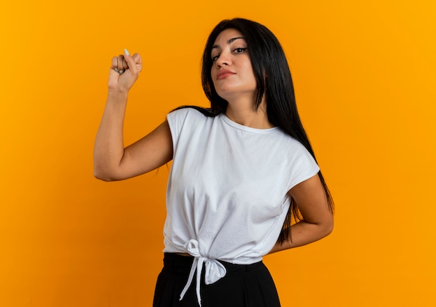 Confident young caucasian girl keeps fist up and holds hand behind 