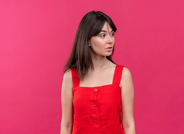 Confident young caucasian girl looking to the side on isolated pink background with copy space