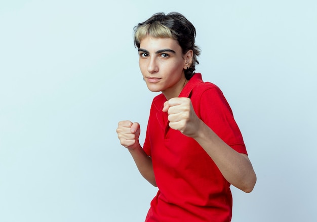 Confident young caucasian girl with pixie haircut doing boxing gesture isolated on white background with copy space