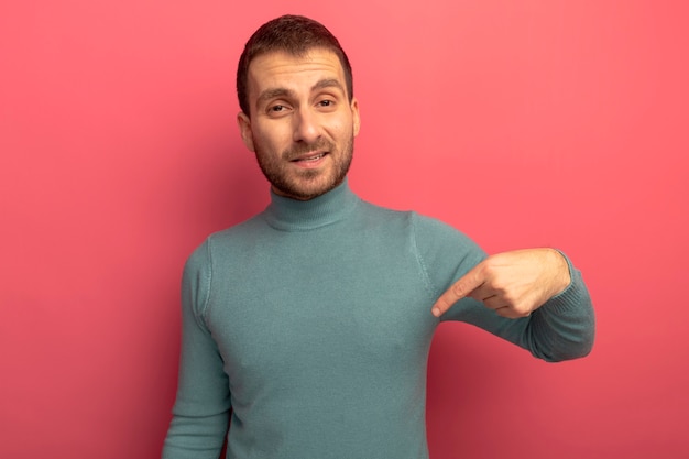 Confident young caucasian man  pointing down isolated on crimson wall with copy space