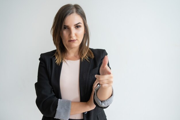 Confident young Caucasian woman in smart suit pointing at you