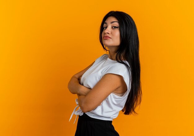 Confident young caucasian woman stands sideways with crossed arms