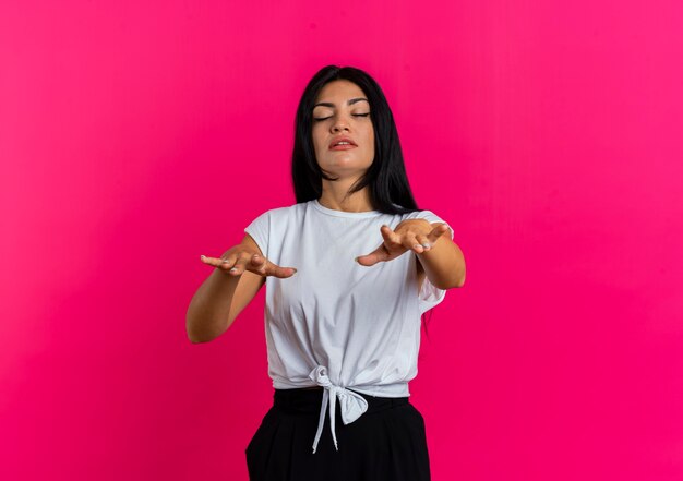 Confident young caucasian woman stands with closed eyes holding hands straight