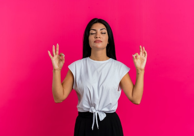Free photo confident young caucasian woman stands with closed eyes pretending to meditate