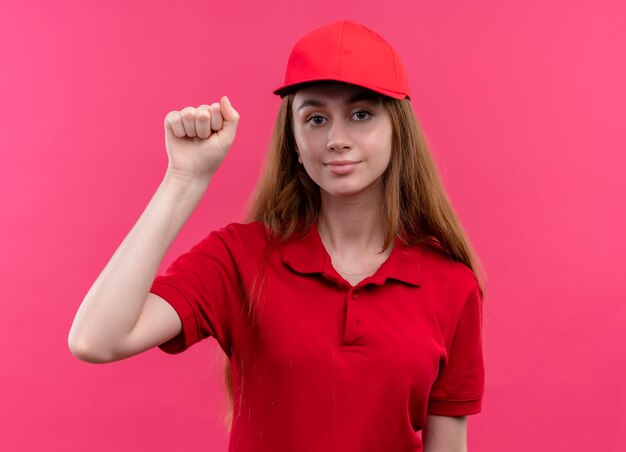 孤立したピンクの空間でノックジェスチャーをしている赤い制服を着た自信を持って若い配達の女の子