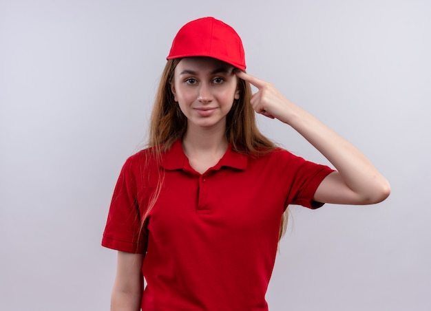 Confident young delivery girl in red uniform putting finger on temple on isolated white space