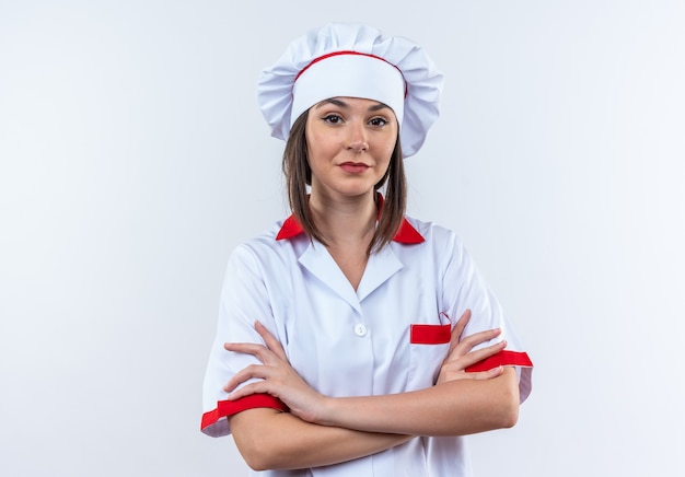 흰색 배경에 고립 된 요리사 유니폼 횡단 손을 입고 자신감 젊은 여성 요리사