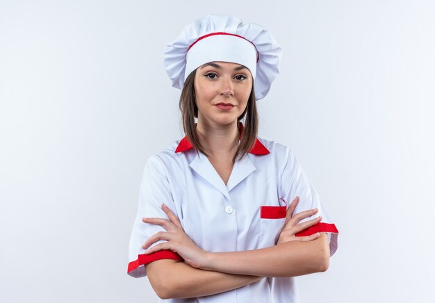 Confident young female cook wearing chef uniform crossing hands isolated on white background