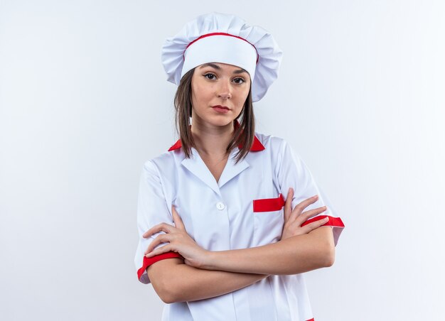 Confident young female cook wearing chef uniform crossing hands isolated on white background