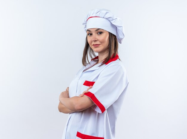白い背景で隔離のシェフの制服交差する手を身に着けている自信を持って若い女性料理人
