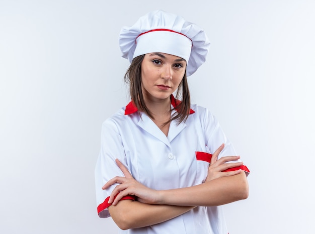 흰 벽에 고립 된 요리사 유니폼 횡단 손을 입고 자신감 젊은 여성 요리사