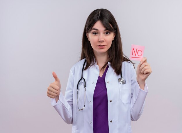 Уверенная молодая женщина-врач в медицинском халате со стетоскопом показывает палец вверх и не держит на изолированном белом фоне с копией пространства
