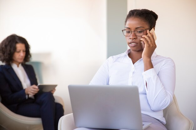 Confident young female manager calling on cellphone