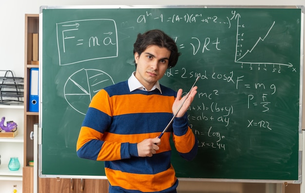 교실에서 칠판 앞에 서 있는 자신감 있는 젊은 기하학 교사