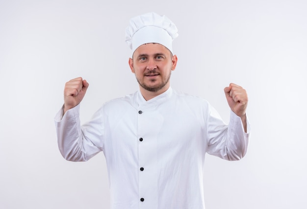 Confident young handsome cook in chef uniform gesturing strong isolated on white wall