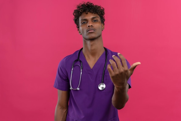 Уверенный в себе молодой красивый темнокожий доктор с вьющимися волосами в фиолетовой форме со стетоскопом