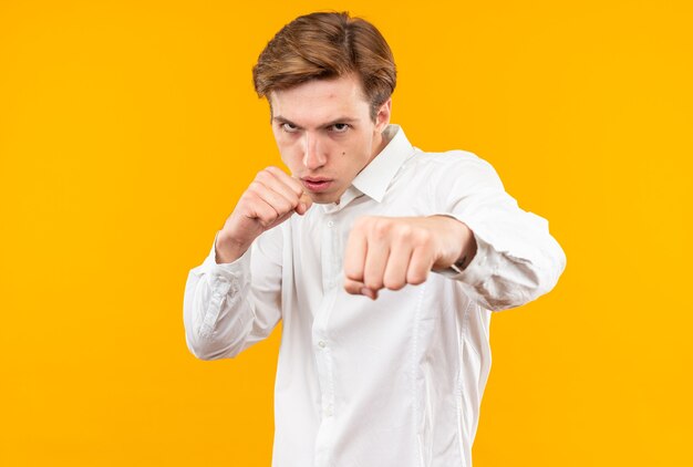 주황색 벽에 격리된 싸움 자세로 서 있는 흰색 셔츠를 입은 자신감 있는 젊은 잘생긴 남자