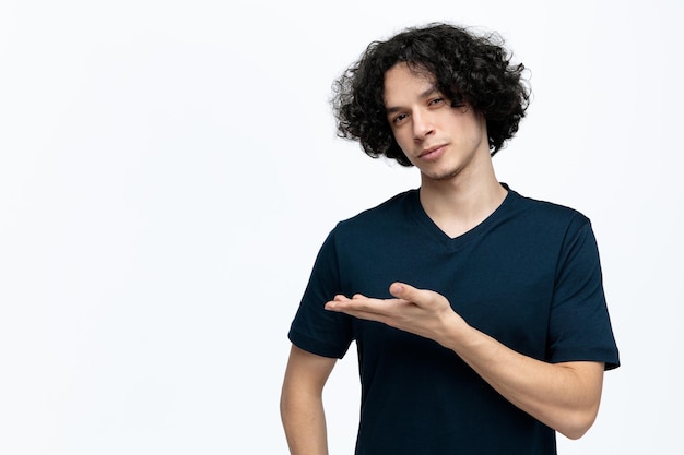 Confident young handsome man looking at camera showing empty hand isolated on white background with copy space