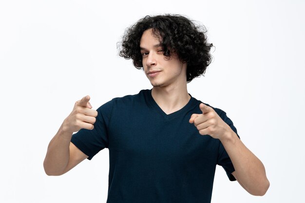 Confident young handsome man looking at camera winking doing you gesture isolated on white background