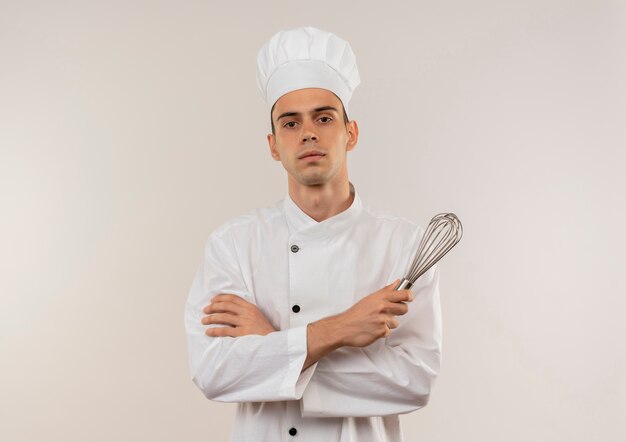 복사 공간이 격리 된 흰 벽에 털을 들고 요리사 유니폼 횡단 손을 입고 자신감 젊은 남성 요리사