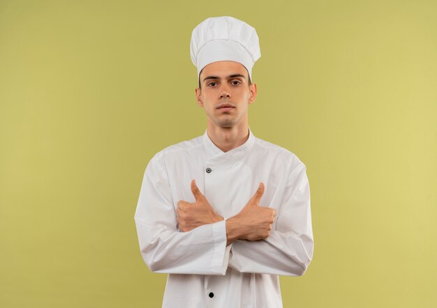 요리사 유니폼을 입고 자신감 젊은 남성 요리사 복사 공간이 격리 된 녹색 벽에 그의 엄지 손가락을 손에 srossing