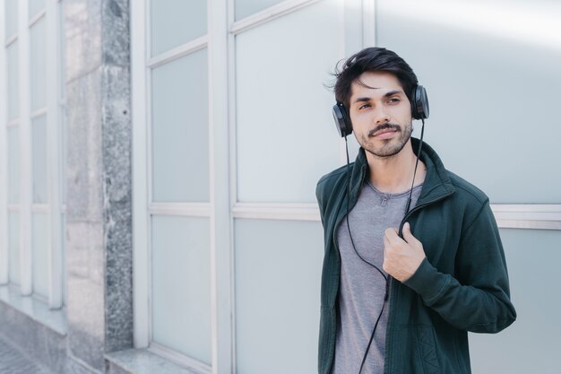 Confident young man in earphones on street