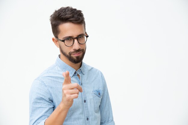 Confident young man pointing at camera