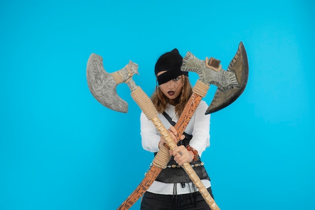 Free photo confident young pirate holding axes and looking at camera. high quality photo