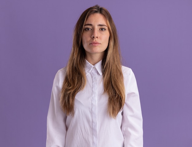 Confident young pretty caucasian girl looks at camera on purple 