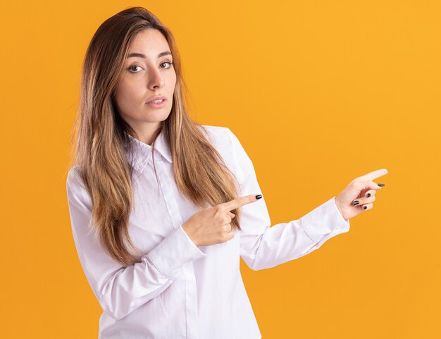 Confident young pretty caucasian girl points at side with two hands