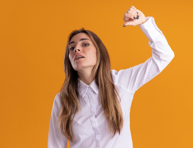 Confident young pretty caucasian girl stands with raised hand pointing at herself on orange 