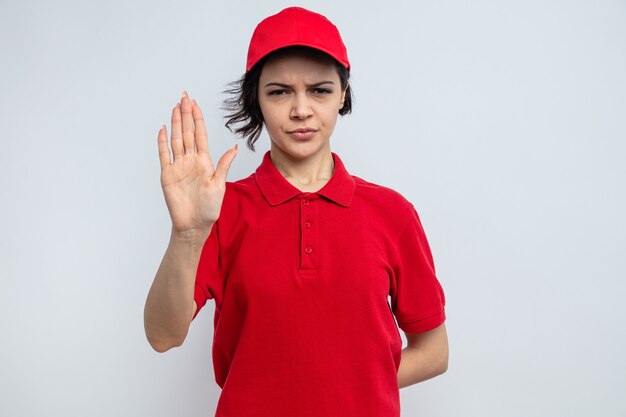 一時停止の標識を身振りで示す自信を持って若いきれいな配達の女性