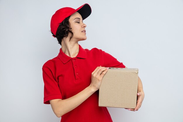 Уверенная молодая красивая женщина доставки, держащая картонную коробку