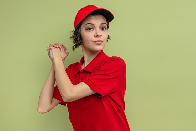 Confident young pretty delivery woman holding hands together