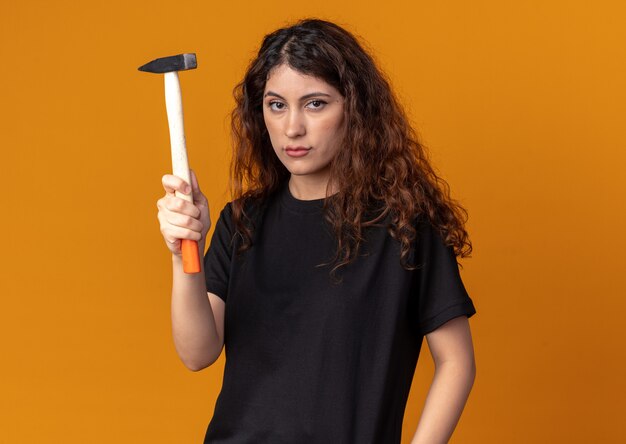 Confident young pretty girl holding hammer 