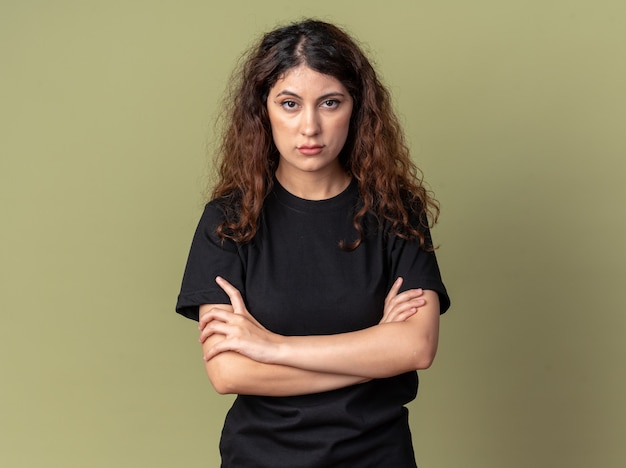 Free photo confident young pretty woman standing with closed posture looking at front isolated on olive green wall with copy space