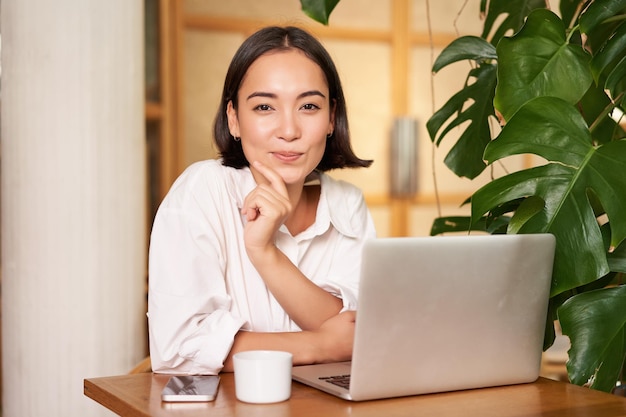 Fiduciosa giovane donna alla moda con il computer portatile seduto al bar e lavora come libero professionista nello spazio di coworking