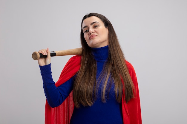 Confident young superhero girl putting baseball bat on shoulder isolated on white background