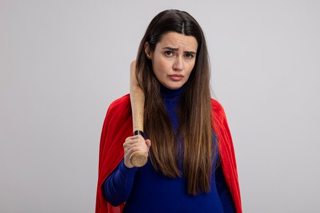 Confident young superhero girl putting baseball bat on shoulder isolated on white