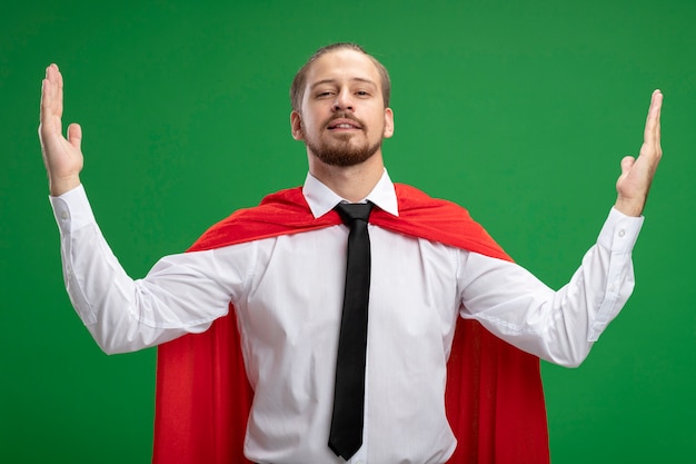 Confident young superhero guy showing size isolated on green